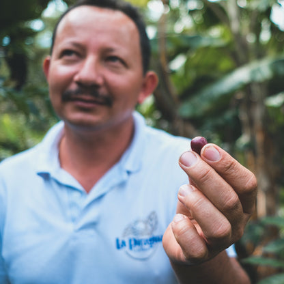 Man holding a cherry in front of a blurred green background
