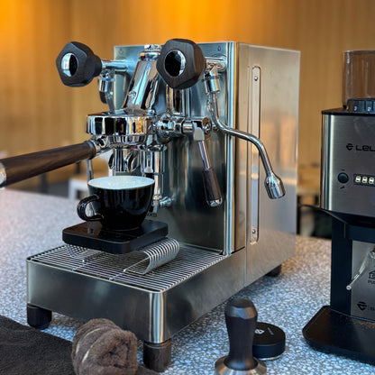 Stylish espresso machine pouring coffee into a black cup for OFFICE COFFEE SUBSCRIPTION at the workplace.