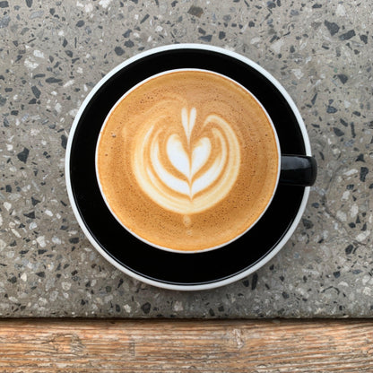 OFFICE COFFEE SUBSCRIPTION - beautifully crafted latte art in a black cup on a textured surface.